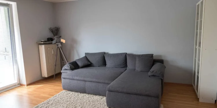 Sala de estar com um sofá cama cinza no centro do cômodo