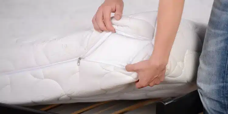 Homem colocando uma capa para colchão em sua cama