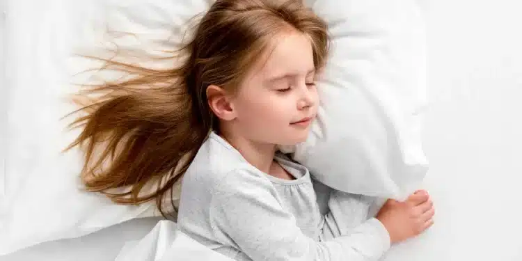 Menina de pijama dormindo sobre travesseiro branco
